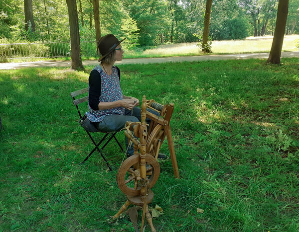 Eine Frau auf einer Wiese am Spinnrad