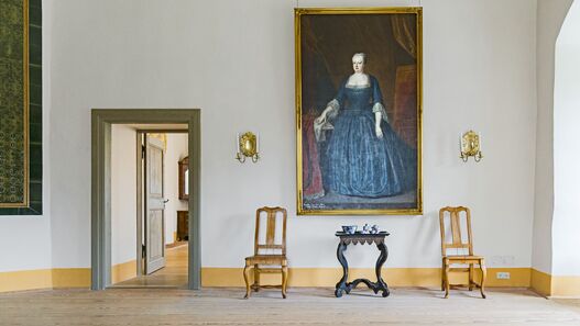Schloss Königs Wusterhausen, Hochparterre, Schlafgemach der Königin Sophie Dorothea, Blick auf Ganzkörperporträt von Sophie Dorothea, darunter ein Tisch und zwei Stühle, links davon eine offene Tür mit Blick in eine Raumflucht