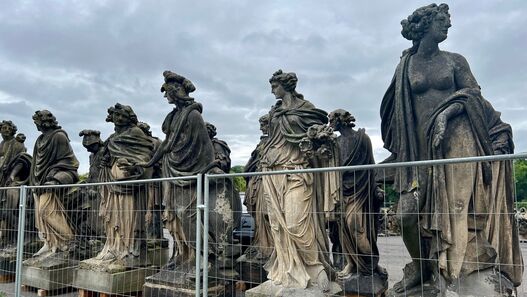 Skulpturen der Dachbalustrade des Neuen Palais – aufgereiht hinter einem Zaun