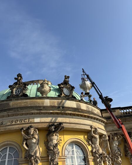 Zinkgussvasen werden mit einem Kran auf die Attika des Schlosses Sanssouci gehoben