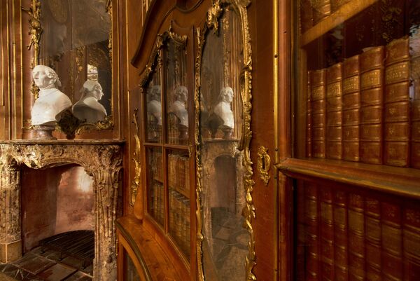 Schloss Sanssouci, Bibliothek Friedrich II., Blick entlang eines der Bücherschränke, mit dem Kamin und der Büste Friedrich des Großen von Cavaceppi im Hintergrund