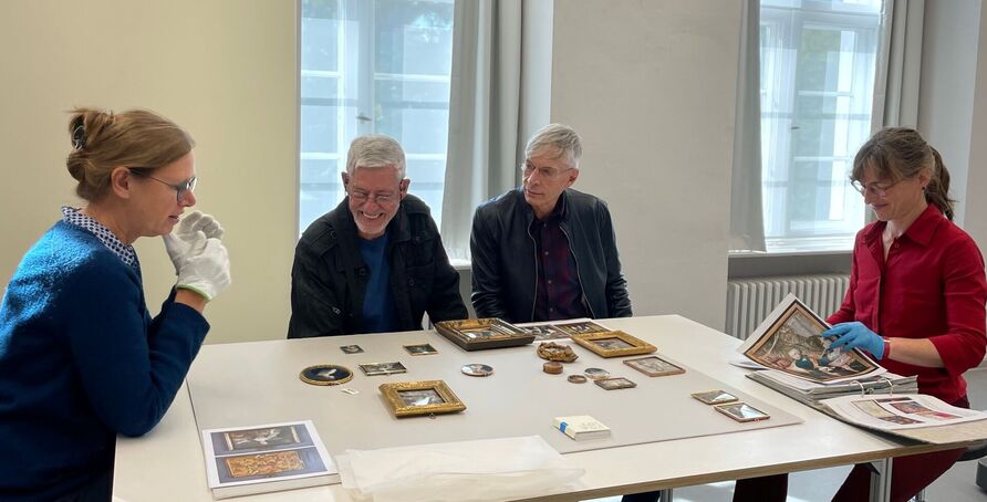 Wilhelm Brökelmann (Mitte links) und sein Partner Andreas Kuppelmayr bei der Vorstellung der restaurierten Miniaturen durch die Restauratorinnen Eva Wenders de Calisse und Sonja Friedmann (rechts)