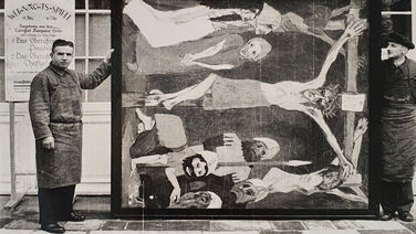 Zwei Angestellte des Kunstdienstes präsentieren Emil Noldes „Kreuzigung“, 1912, Öl/Leinwand, 220,5 × 193,5 cm (Wvz. Urban 477) vor dem Schloss Schönhausen, Foto: Günter Ranft (vermutlich) © Nolde Stiftung Seebüll Kunst – Menschen – Macht