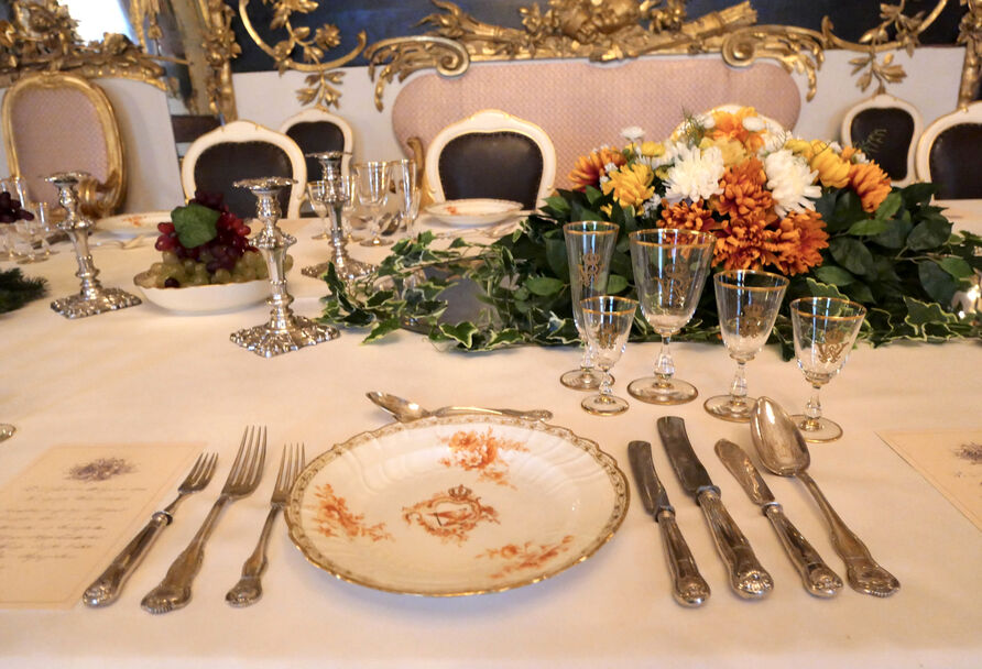 Eingedeckter einzelner Platz mit Teller, Gläsern, Besteck und Menükarte