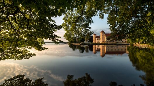 Blick über den Grienericksee auf das Schloss Rheinsberg in der Abendsonne