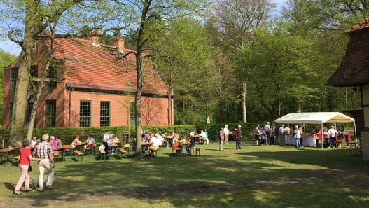 Jagdschloss Stern im Frühling und Gästen auf Bierzeltgarnituren im Freien